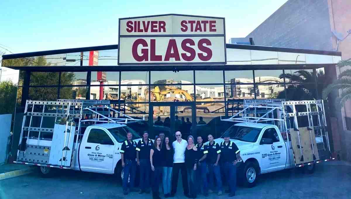 Team Of Silver State Glass & Mirror Co. &Amp; Mirror Employees Standing In Front Of The Company Building With Branded Trucks.