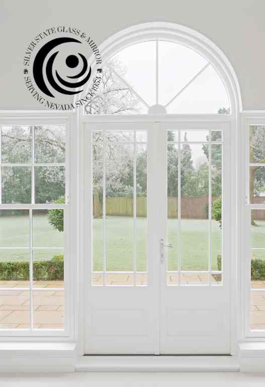 Elegant White-Framed French Doors With Arched Transom And Large Glass Panels Overlooking A Garden.