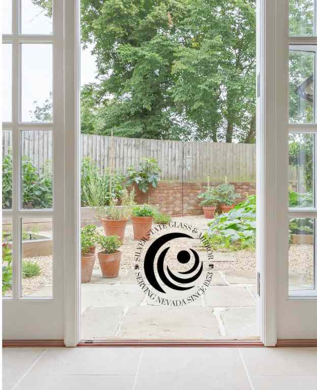 French Doors Opening To A Cozy Patio Garden With Potted Plants And Lush Greenery.