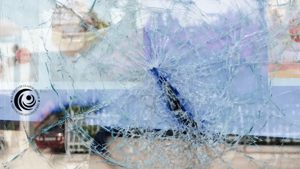 Shattered glass panel with intricate crack patterns, highlighting extensive damage and featuring the Silver State Glass & Mirror logo.