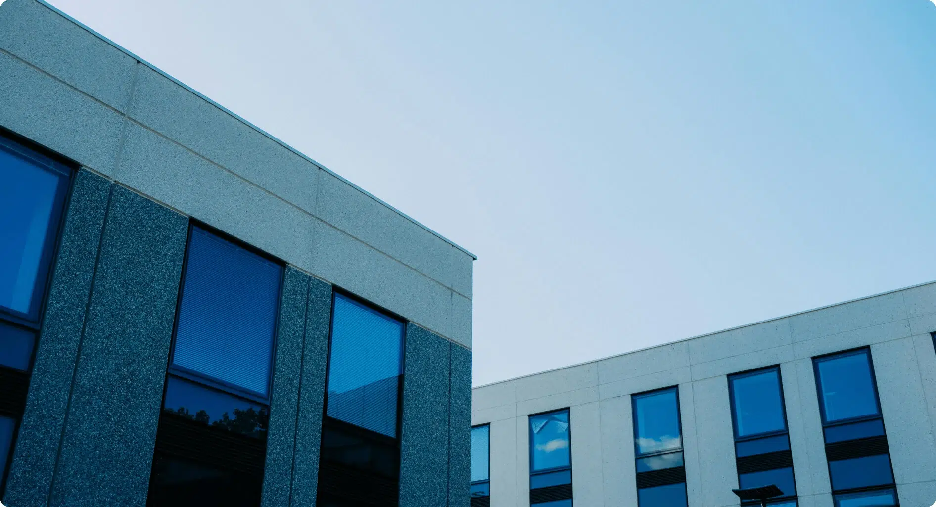Modern commercial building exterior with large blue-tinted windows and a clear sky background.