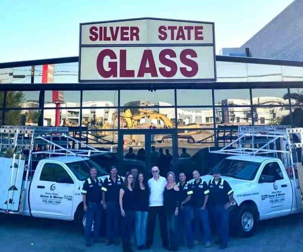 Team Of Silver State Glass & Mirror Co. &Amp; Mirror Employees Standing In Front Of The Company Building With Branded Trucks.