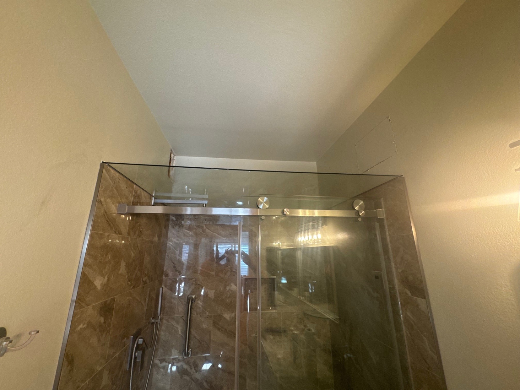 A sliding glass shower enclosure with marble tile and chrome hardware
