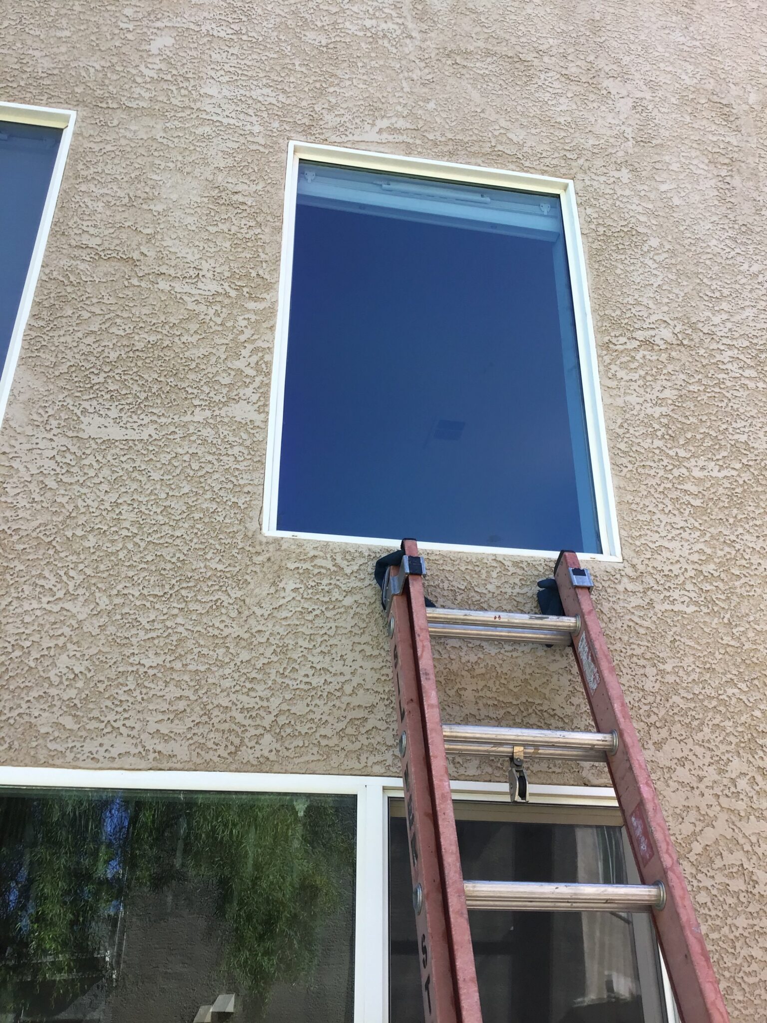 Window Replacement & Installation in Las Vegas 3 A new window set into a stucco wall, ladder alongside