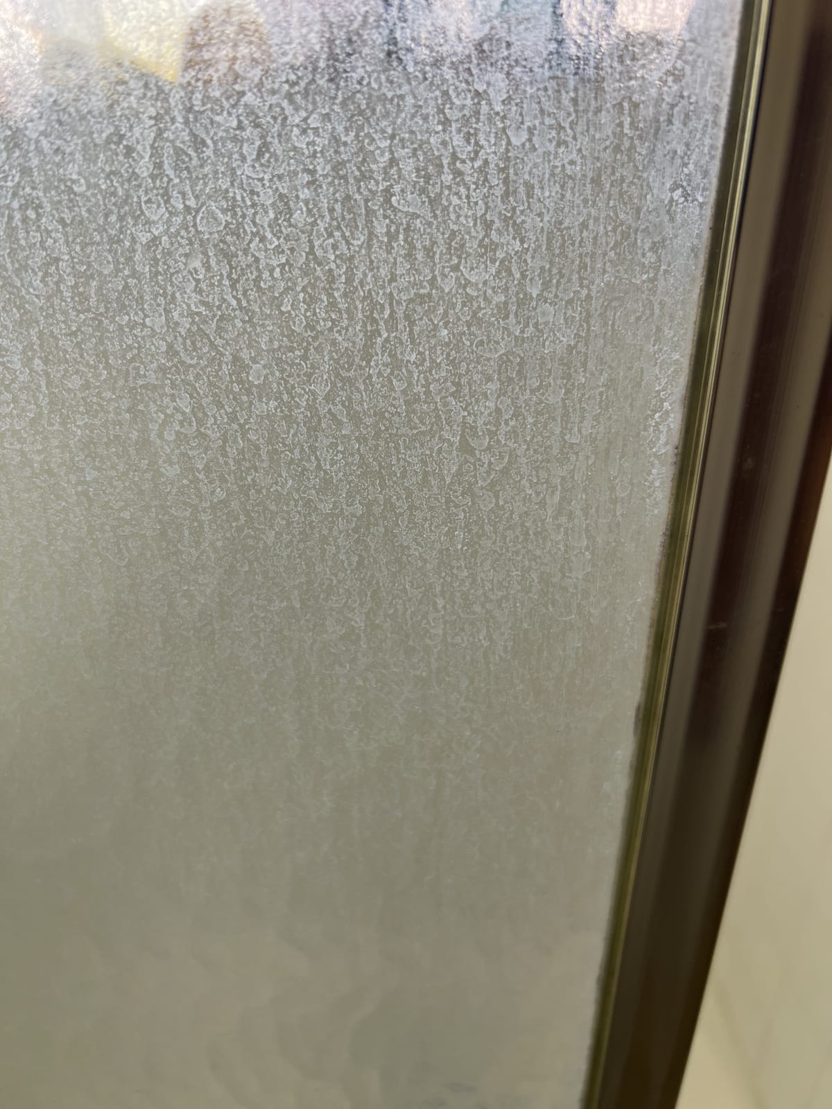 Custom Shower Doors & Glass Enclosures in Las Vegas 2 Glass etched with heavy white hard-water mineral scale along a bronze frame edge