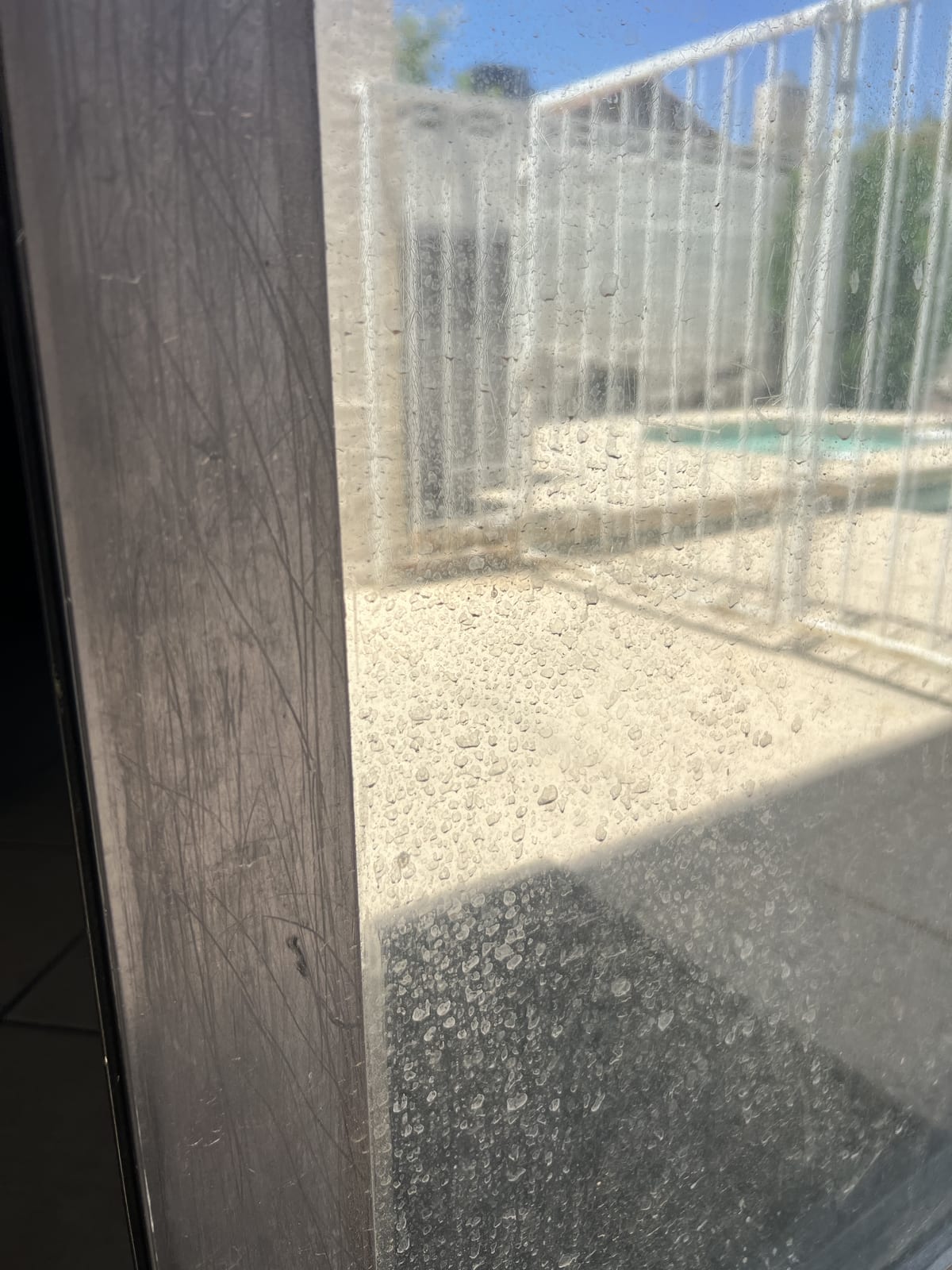 Custom Shower Doors & Glass Enclosures in Las Vegas 3 Extreme close-up of hard-water spotting and fine scratches on a glass door surface