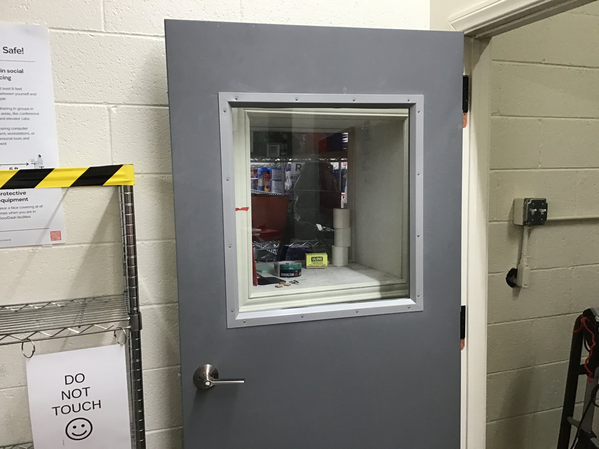 Gray hollow metal door with a glass vision lite in a commercial back room
