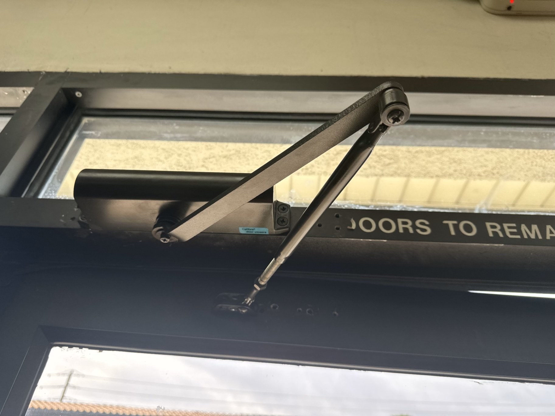 Surface mounted door closer with a regular arm on an aluminum entrance door